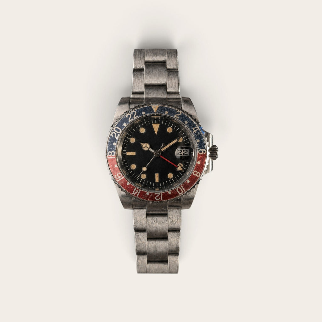 Full view of an aged black-red GMT automatic watch with a three-link bracelet