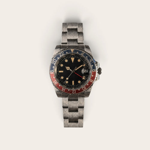 Full view of an aged black-red GMT automatic watch with a three-link bracelet