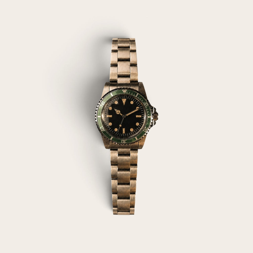 Full view of an aged green-bezel diver on a three-link metal bracelet