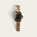 Full view of an aged green-bezel diver on a three-link metal bracelet