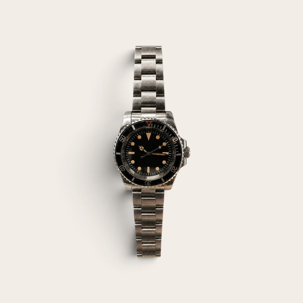Faded-bezel vintage dive watch with warm-tone lume on a neutral background