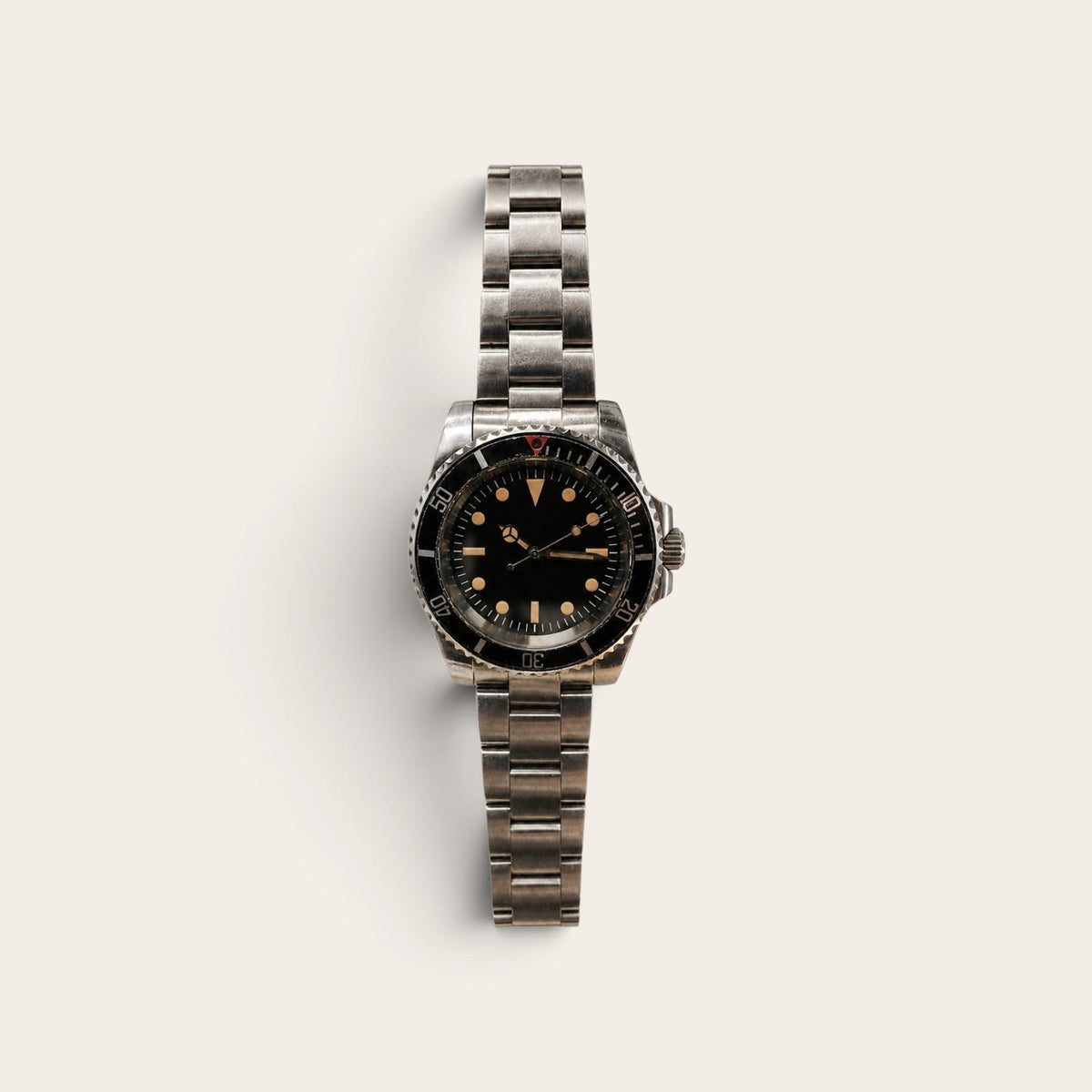 Faded-bezel vintage dive watch with warm-tone lume on a neutral background