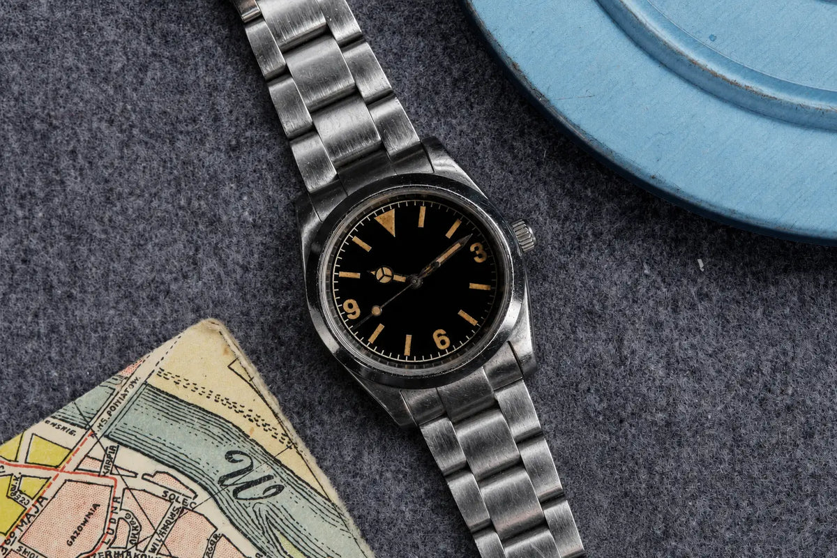 Aged 36mm vintage 3-6-9 automatic field watch beside an old map and blue watch case