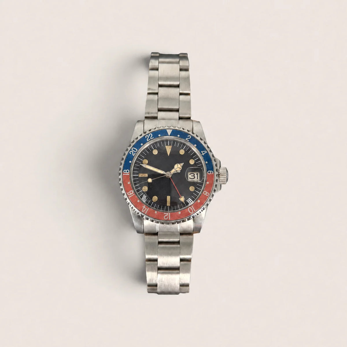 Front view of the vintage red-blue GMT watch with aged bezel, black dial and red GMT hand