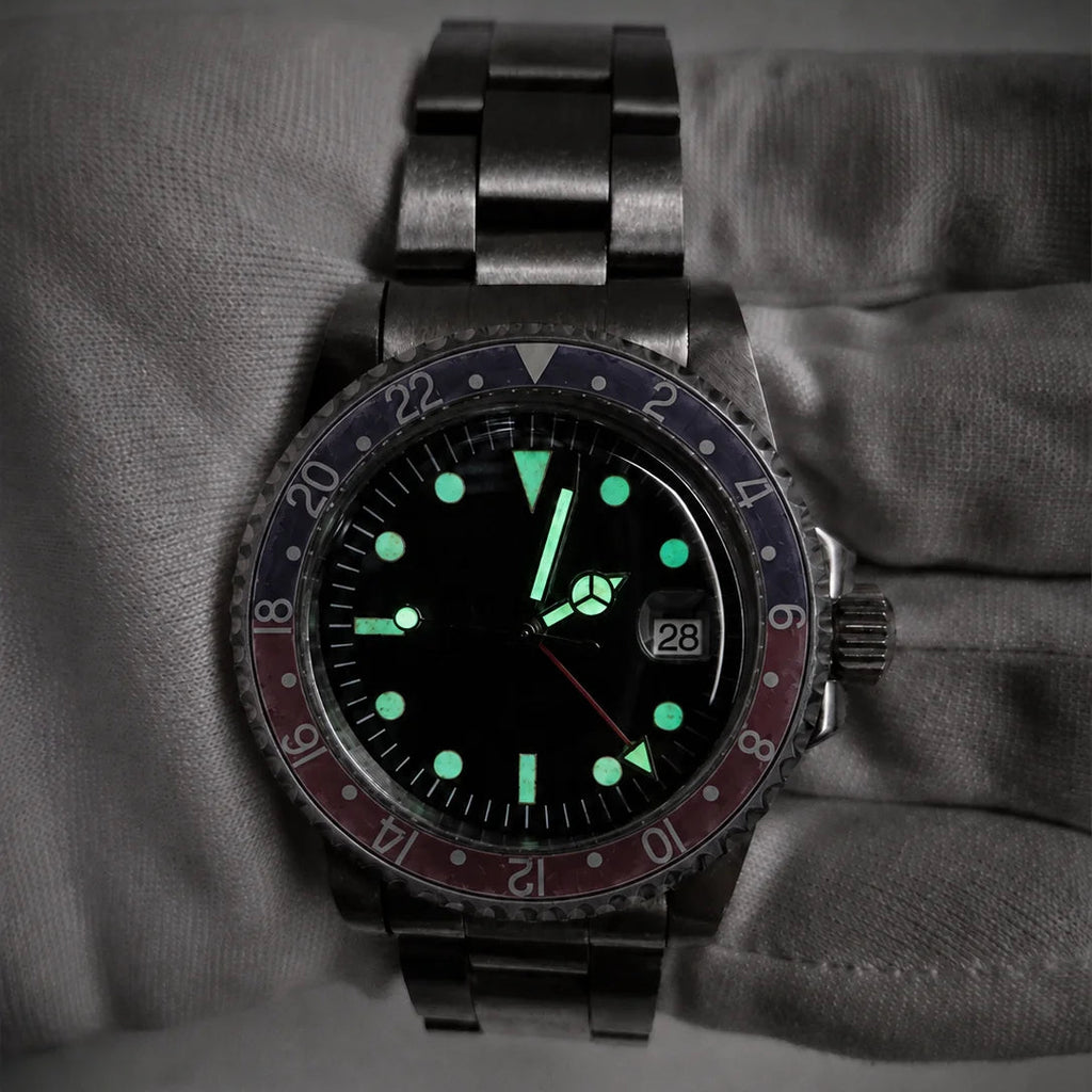 Vintage red-blue GMT automatic watch glowing with green lume in low light