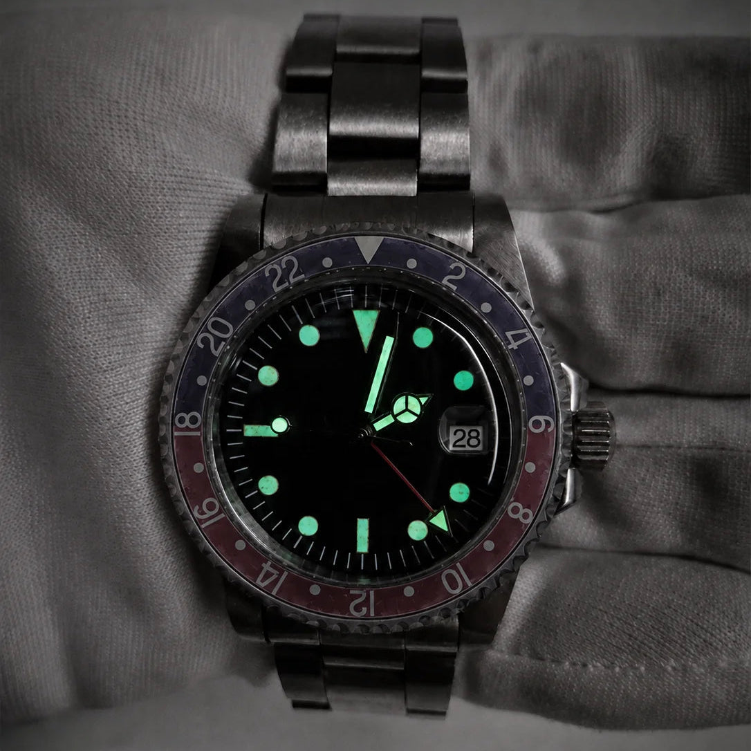Vintage red-blue GMT automatic watch glowing with green lume in low light