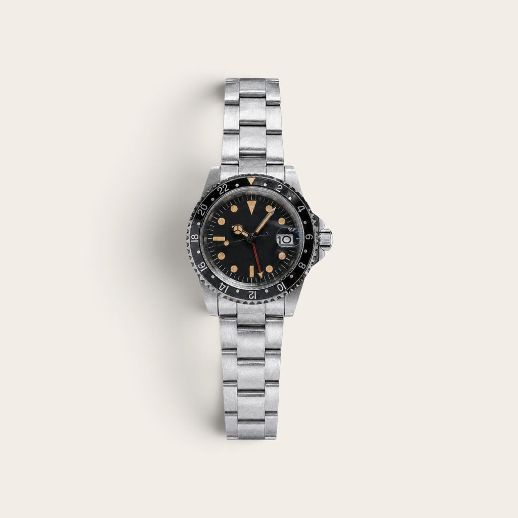 Vintage-style black-bezel GMT watch with a weathered steel case and bracelet